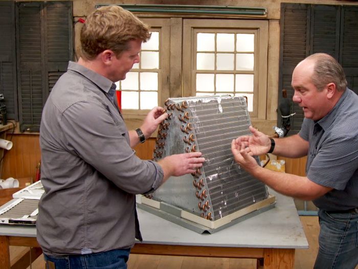 Photo of two people looking at an air conditioning system that uses Freon, which is now a banned chemical.