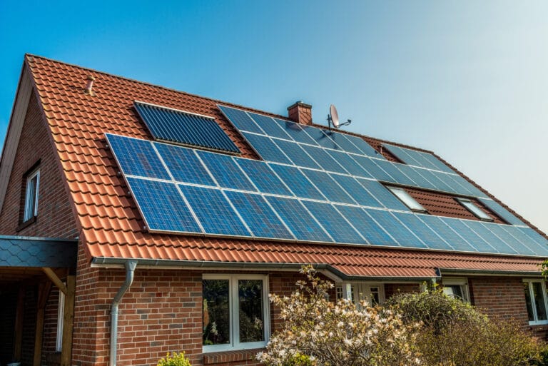 A closeup of a brick house with solar panels on its muted red roof